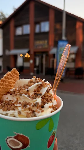 Eisbecher mit Sahne, Krokant und Waffelstück vor der Eisdiele