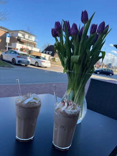 Zwei Eiskaffees mit Sahne auf dem Terrassentisch, dahinter Tulpen